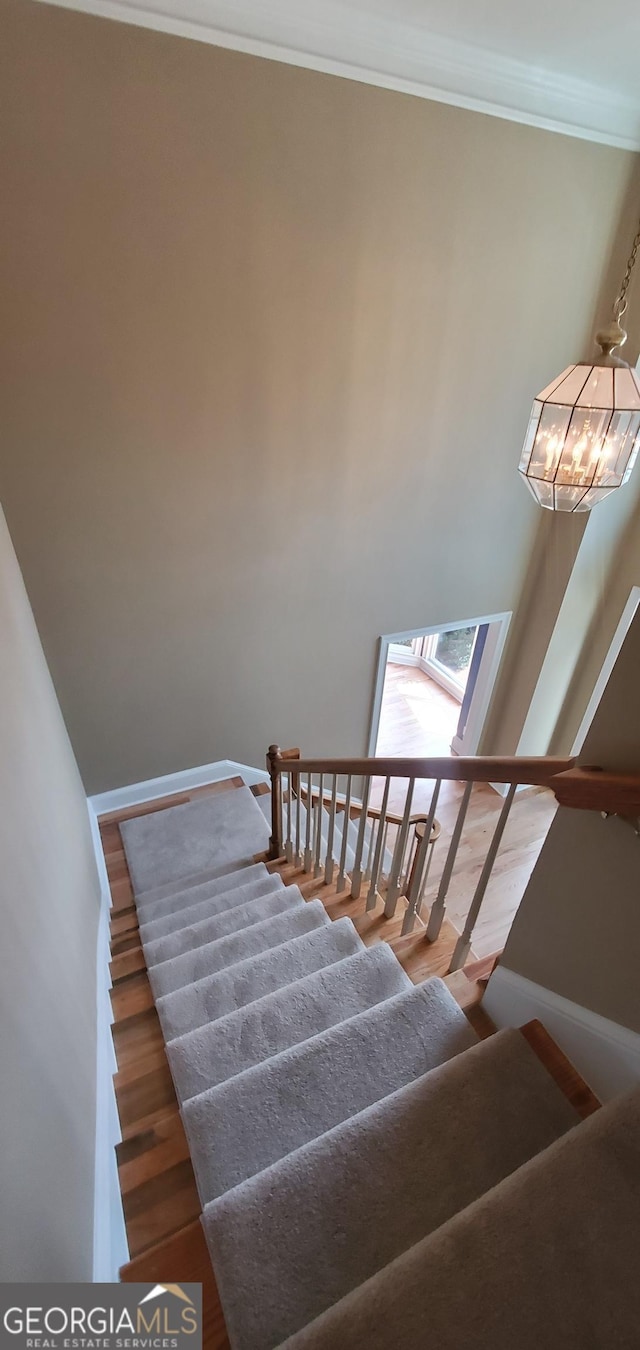 2899 Greystone Cv N, Atlanta, GA 30341 - stairway featuring crown molding, a chandelier, baseboards, and wood finished floors