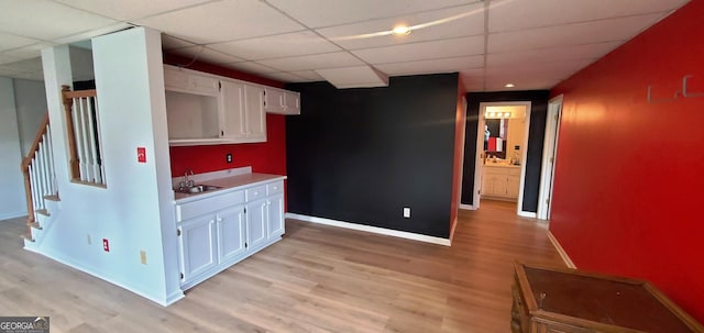2899 Greystone Cv N, Atlanta, GA 30341 - kitchen featuring a sink, light wood-type flooring, white cabinetry, a paneled ceiling, and baseboards