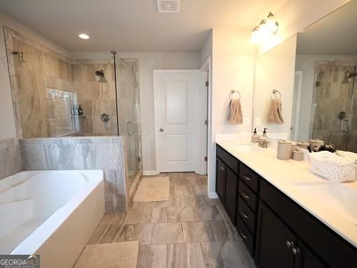 full bathroom featuring a sink, visible vents, a bath, and a shower stall