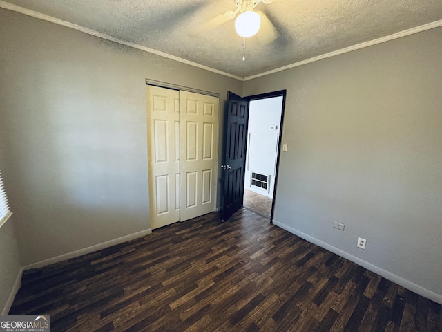 unfurnished bedroom featuring visible vents, dark wood finished floors, a textured ceiling, crown molding, and a closet