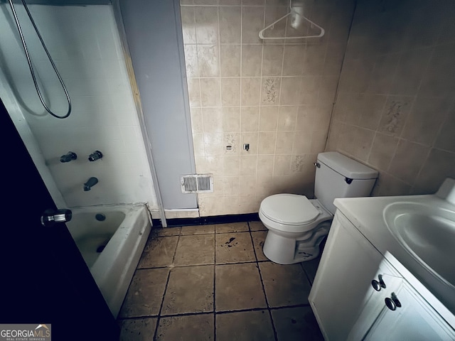 bathroom featuring tile patterned flooring, toilet, vanity, visible vents, and tile walls