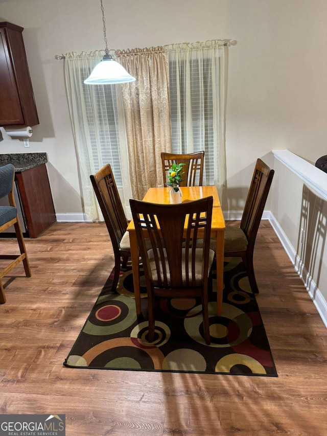 dining space featuring dark wood-type flooring and baseboards