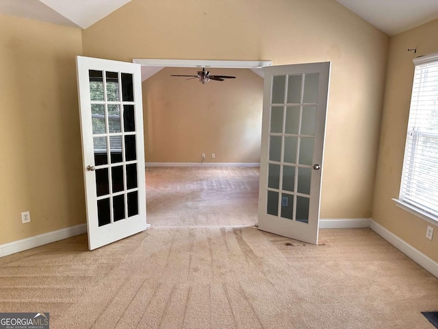 unfurnished room with carpet floors, a healthy amount of sunlight, vaulted ceiling, and baseboards