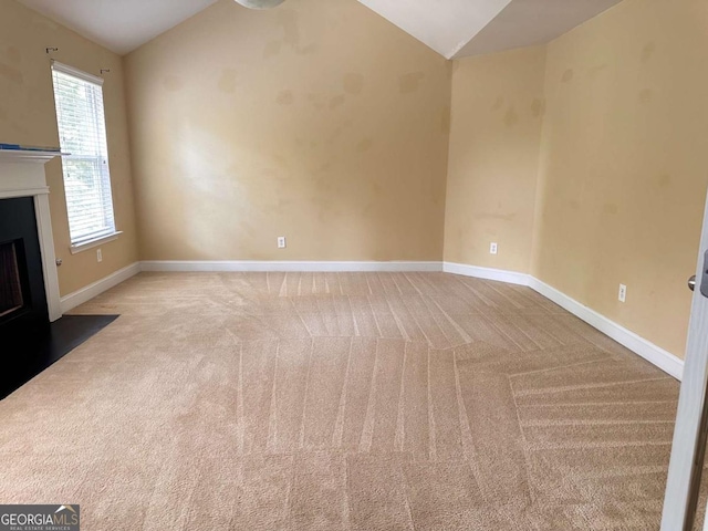 unfurnished living room featuring a fireplace with flush hearth, lofted ceiling, carpet floors, and baseboards