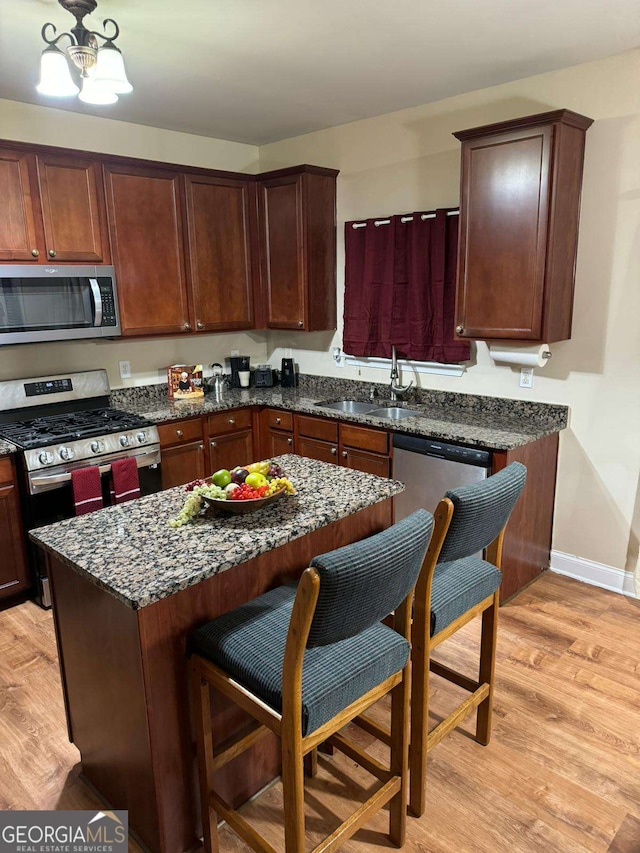 kitchen featuring light wood-style floors, a kitchen bar, stainless steel appliances, and a sink