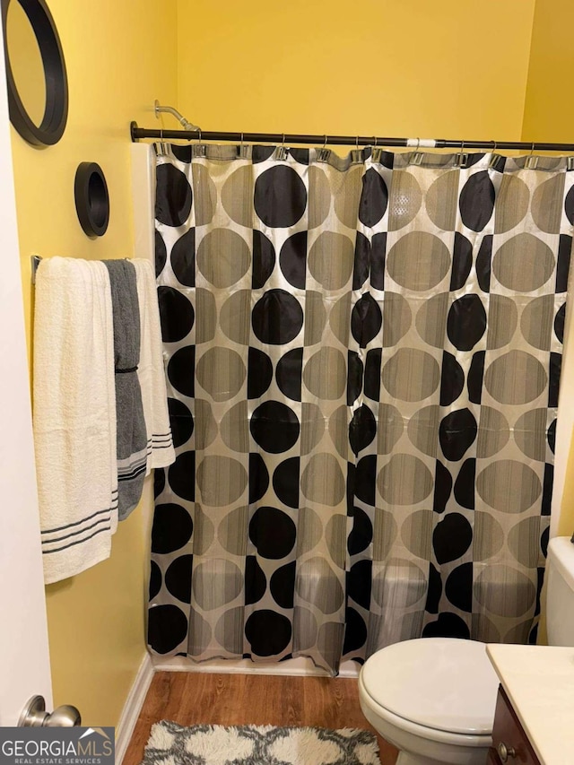 full bathroom with a shower with shower curtain, vanity, toilet, and wood finished floors