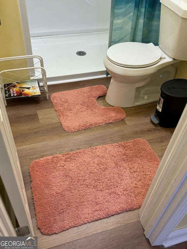 bathroom featuring a stall shower, wood finished floors, and toilet