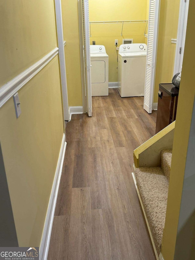 laundry room with laundry area, a wainscoted wall, wood finished floors, and independent washer and dryer