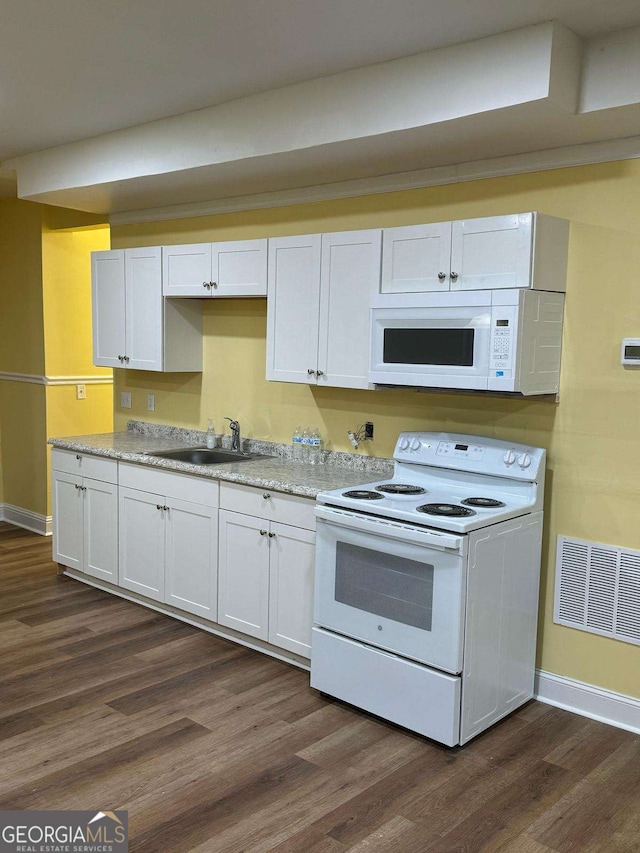 kitchen featuring white appliances, visible vents, dark wood-type flooring, and a sink