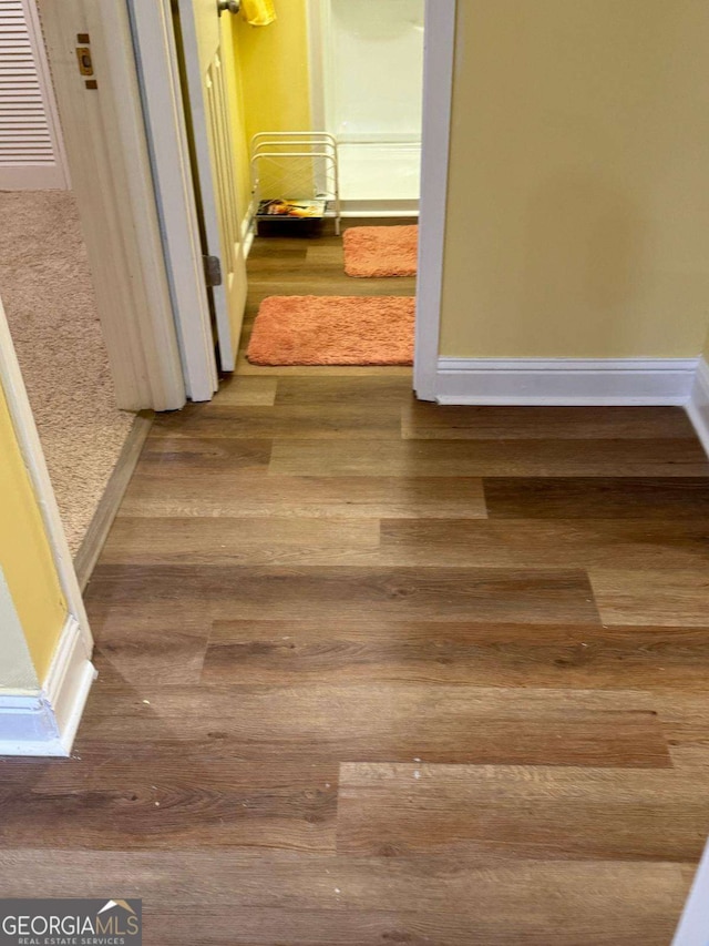 corridor with wood finished floors and baseboards