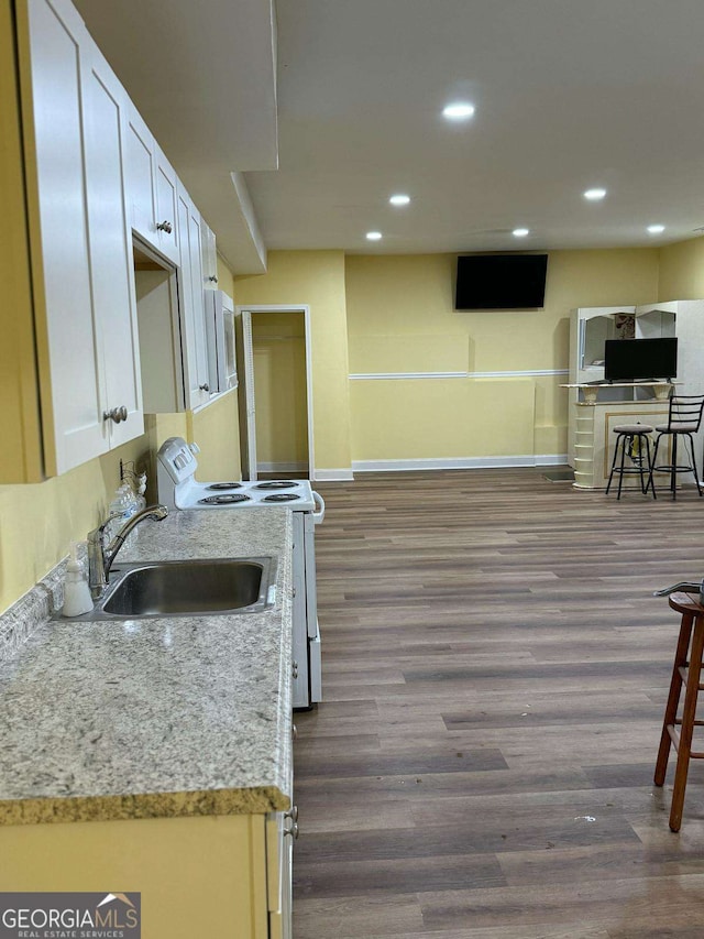 kitchen with recessed lighting, dark wood-type flooring, white cabinetry, a sink, and white appliances