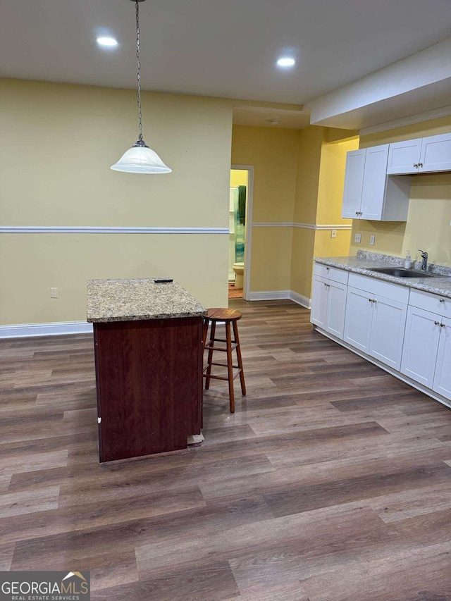 kitchen featuring dark wood-style floors, white cabinetry, a sink, and baseboards