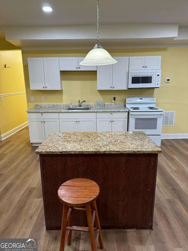 kitchen with white appliances, dark wood-style flooring, a sink, visible vents, and hanging light fixtures