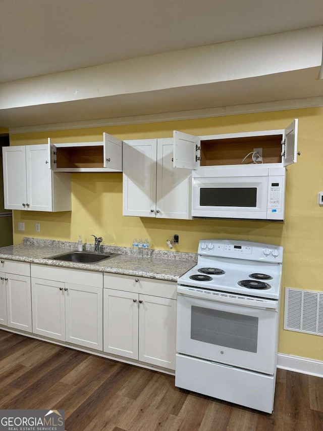 kitchen with white appliances, visible vents, white cabinets, dark wood-style floors, and a sink