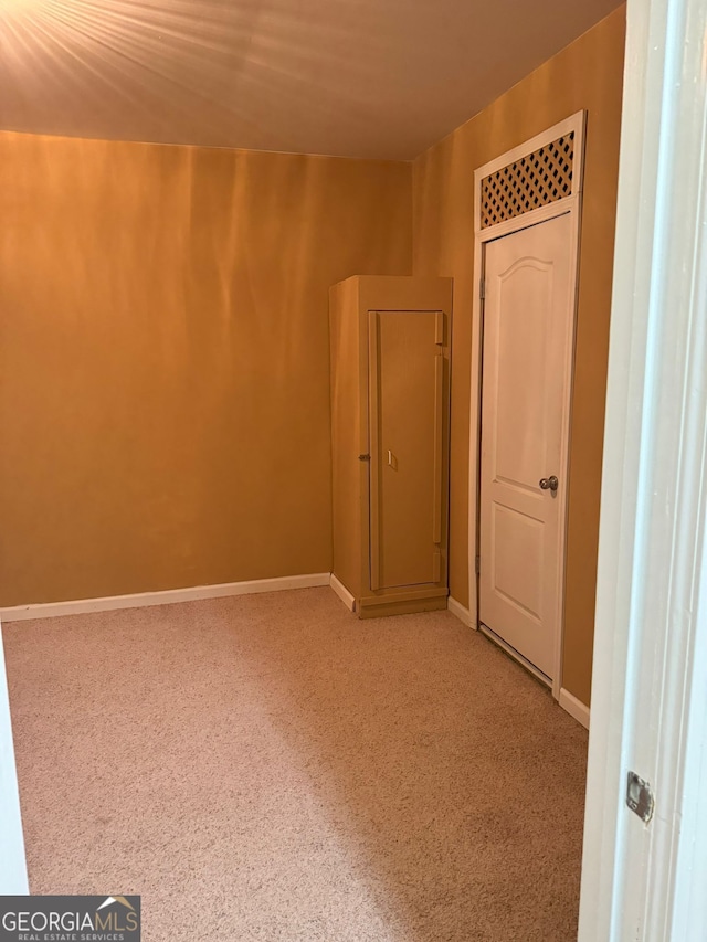 spare room with baseboards and light colored carpet