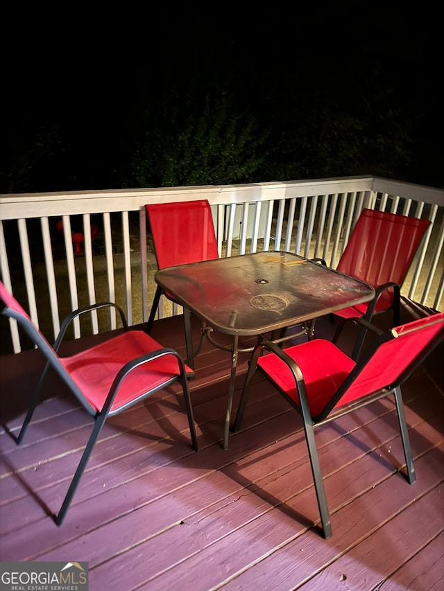 deck at night featuring outdoor dining space