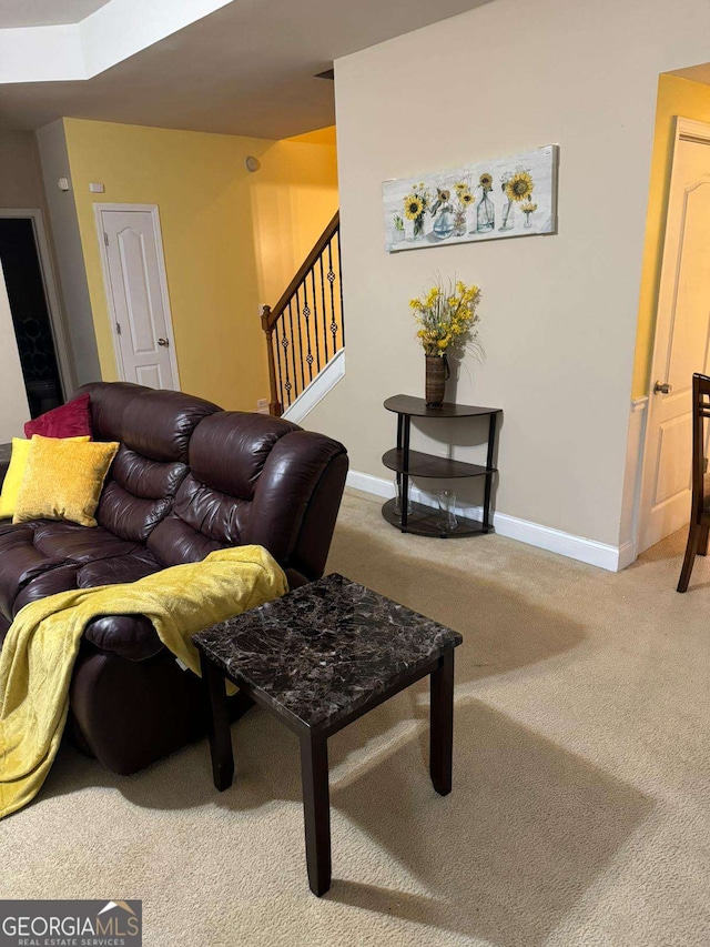 carpeted living room with stairs and baseboards