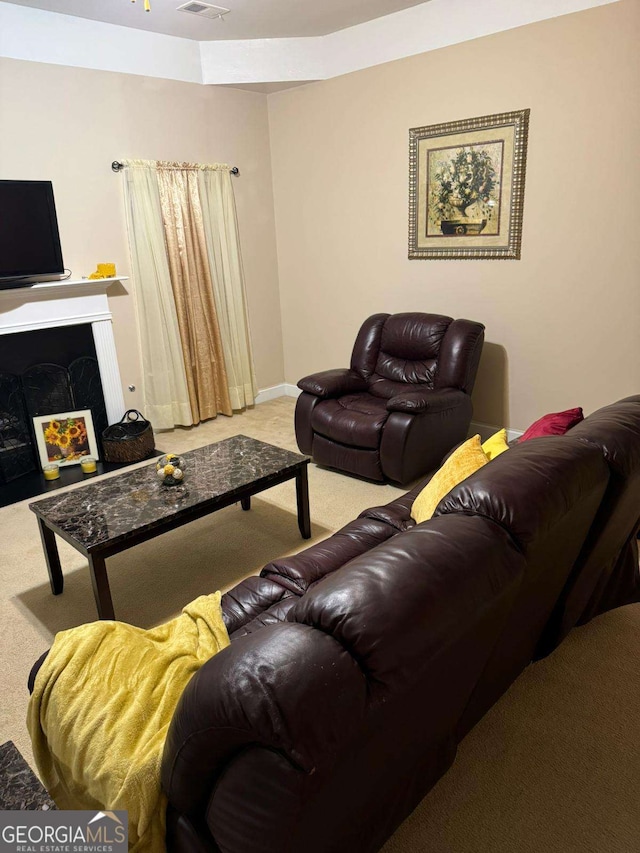 carpeted living area featuring a warm lit fireplace and visible vents