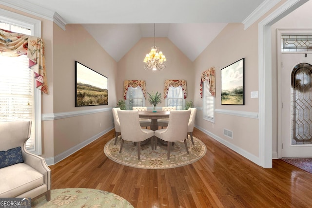 dining space featuring a chandelier, wood finished floors, visible vents, baseboards, and vaulted ceiling