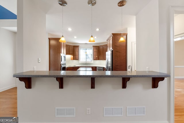 kitchen featuring stainless steel appliances, light wood-type flooring, and visible vents