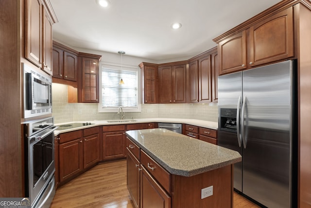 kitchen with light wood finished floors, stainless steel appliances, a sink, and a warming drawer