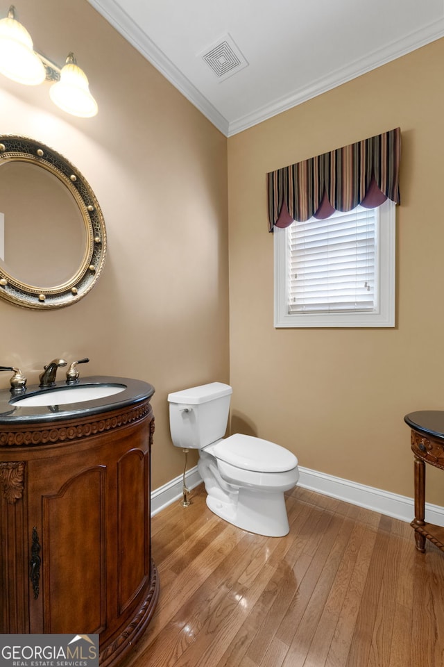 bathroom with toilet, wood finished floors, vanity, visible vents, and ornamental molding