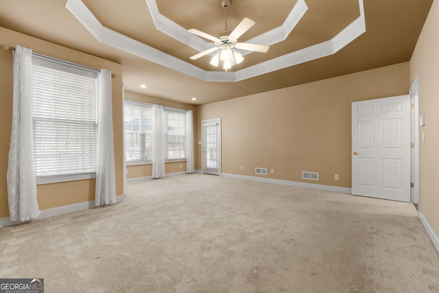 carpeted spare room with baseboards, a raised ceiling, visible vents, and crown molding