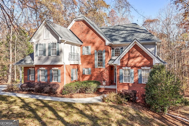 view of front of house featuring brick siding, a front lawn, a shingled roof, and stucco siding