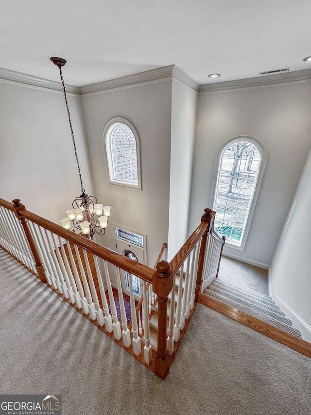 stairway featuring carpet floors, visible vents, a notable chandelier, and ornamental molding