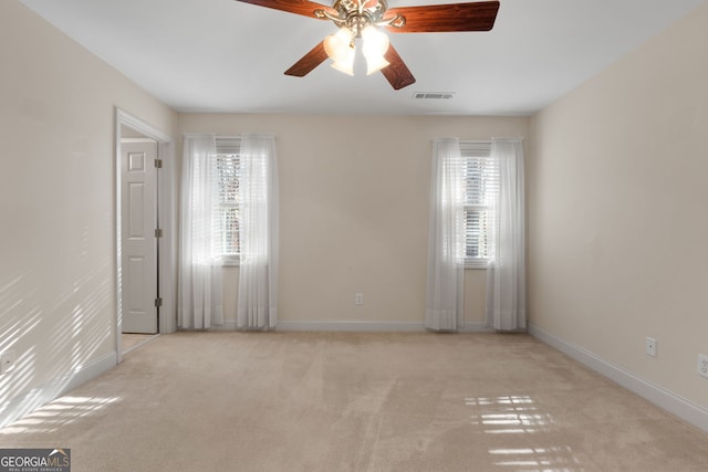 unfurnished room with carpet floors, baseboards, visible vents, and a wealth of natural light