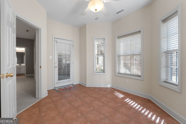 empty room with a ceiling fan, visible vents, baseboards, and light tile patterned floors