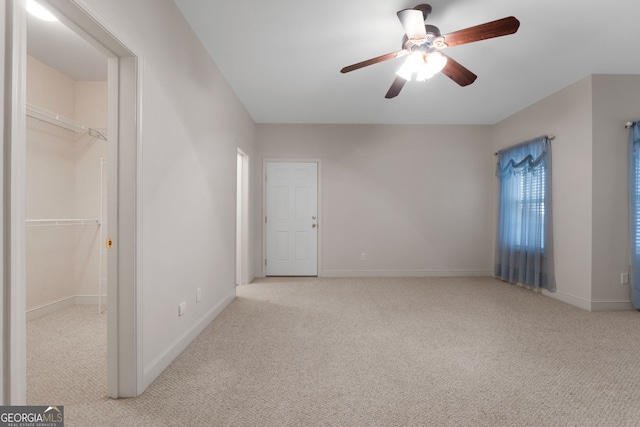 carpeted spare room featuring baseboards and a ceiling fan