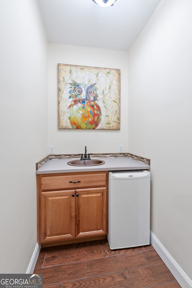 interior space with a sink, baseboards, dark wood-style flooring, and dishwasher