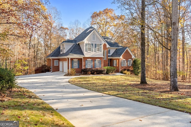 view of front facade with concrete driveway, brick siding, roof with shingles, and a front yard