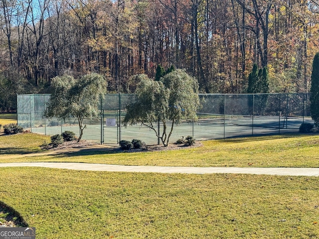 view of sport court with a lawn, fence, and a gate