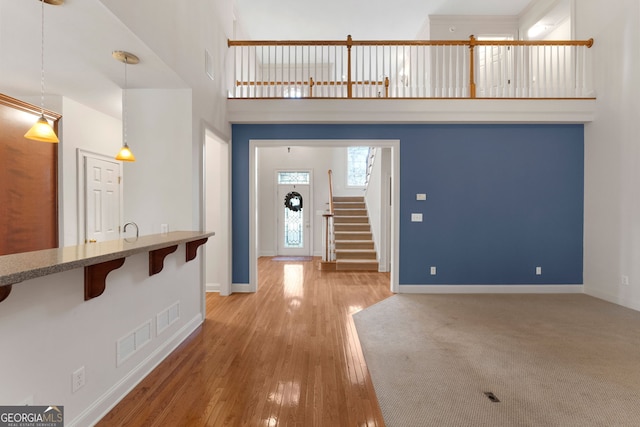 foyer featuring baseboards, a high ceiling, stairway, and wood finished floors