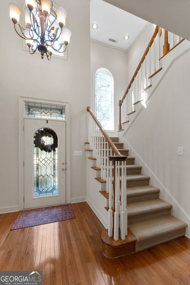 foyer with baseboards, visible vents, hardwood / wood-style floors, and ornamental molding