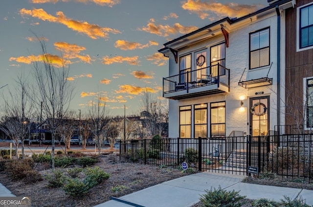 exterior entry at dusk featuring fence and a balcony