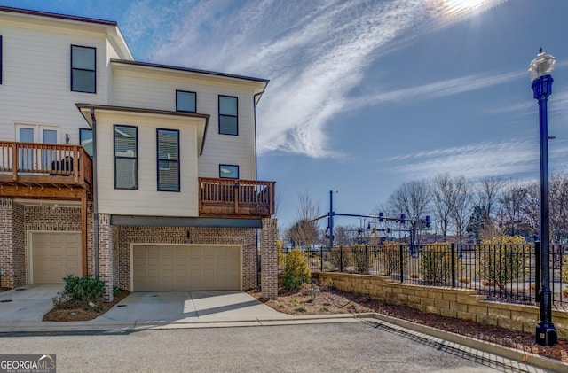 exterior space featuring driveway, a garage, fence, and brick siding