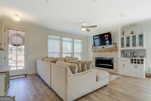 living area with ornamental molding, a wealth of natural light, and light wood-style flooring