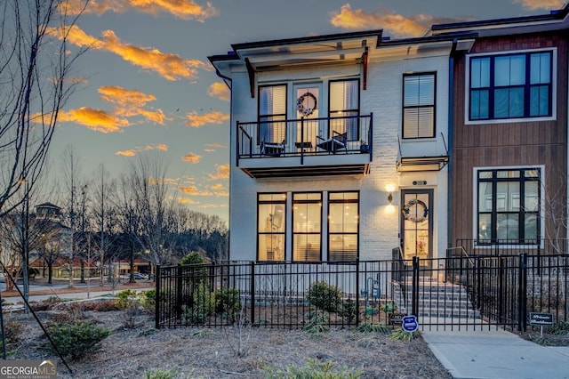 view of front facade featuring brick siding, fence, and a balcony