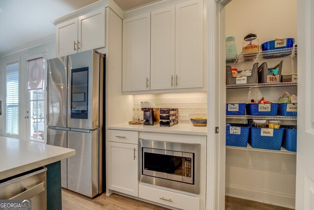 kitchen featuring light wood-type flooring, white cabinetry, appliances with stainless steel finishes, and light countertops