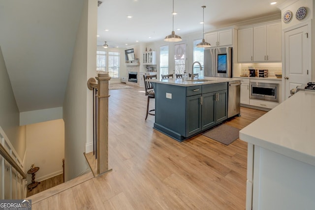 kitchen with light wood finished floors, a fireplace, appliances with stainless steel finishes, and light countertops