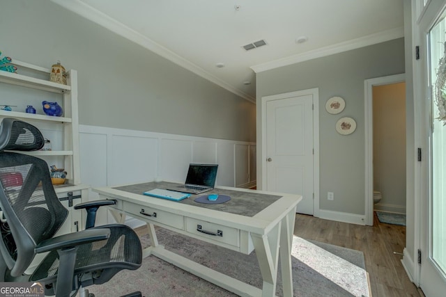 office space with crown molding, visible vents, a decorative wall, wainscoting, and light wood-type flooring