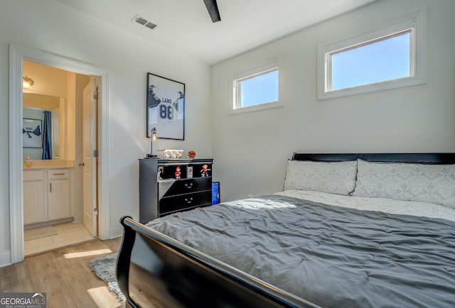 bedroom featuring ensuite bathroom, visible vents, and light wood-style floors