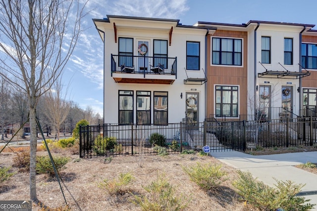 townhome / multi-family property with a balcony and a fenced front yard