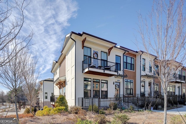 view of front facade featuring brick siding, fence, and stucco siding