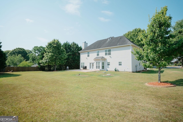 back of property with a patio area, a chimney, fence, and a lawn