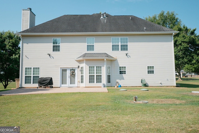 back of house with a patio area, a yard, and a chimney