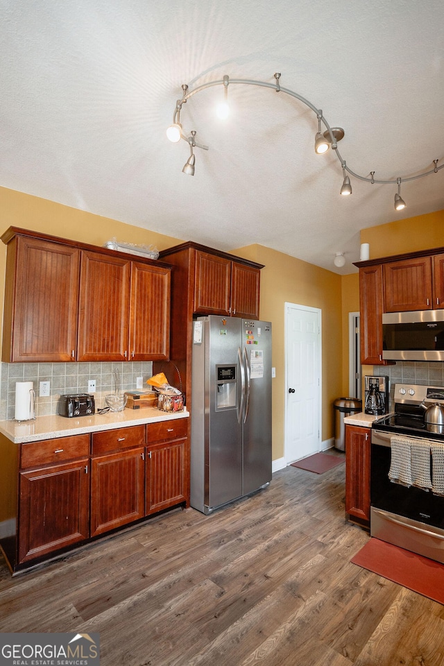 kitchen with dark wood-style floors, appliances with stainless steel finishes, light countertops, and backsplash